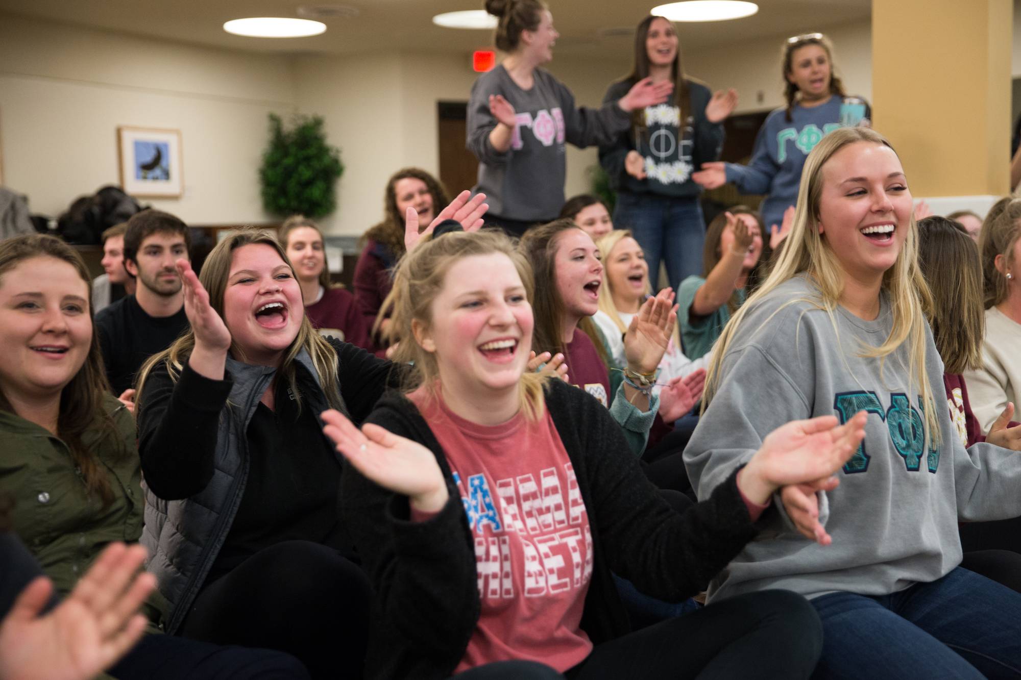 A group of greek life students laughing and clapping